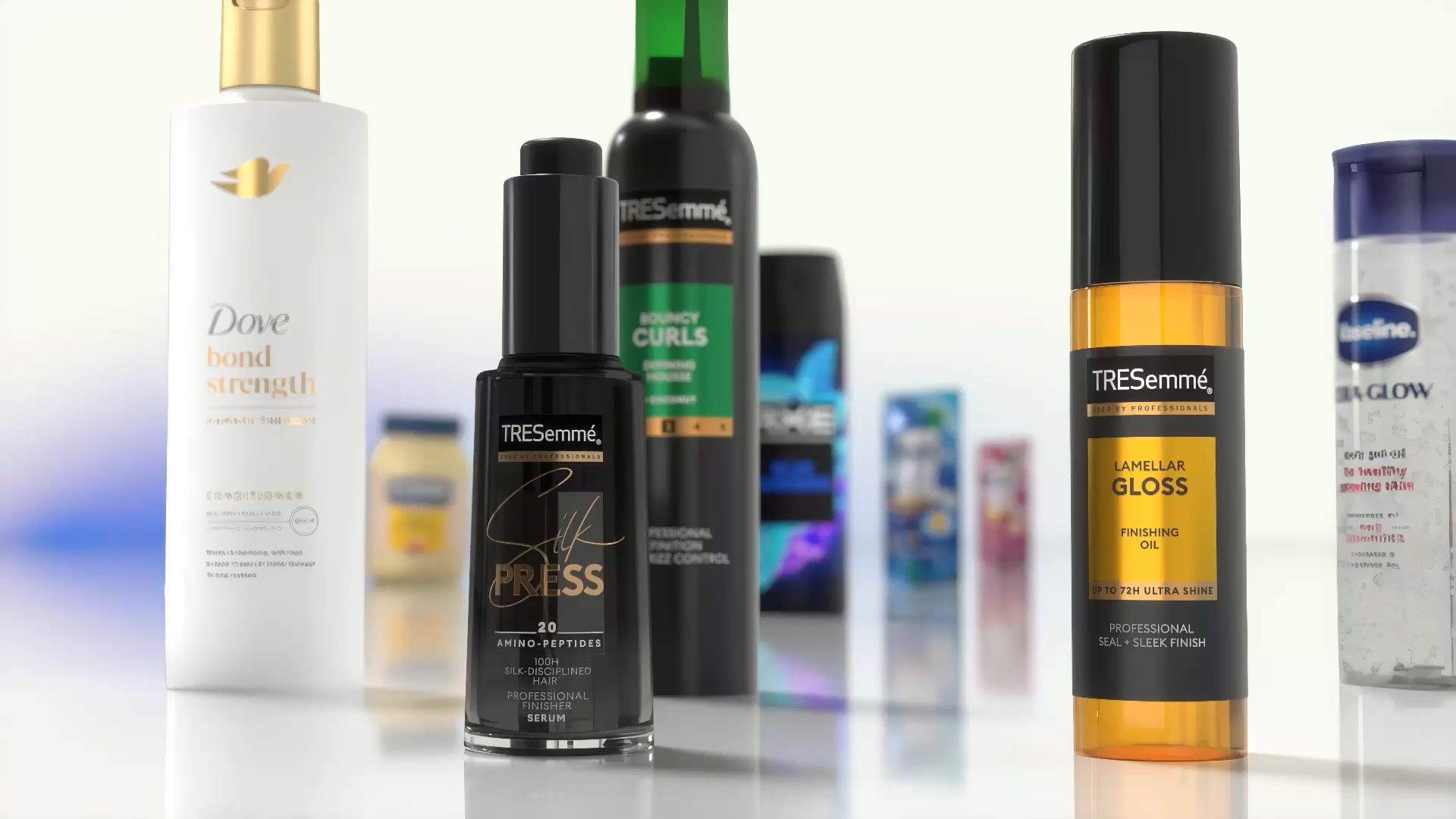 Närbild av diverse hår- och kroppsvårdsprodukter som visas på en reflekterande yta. Synliga föremål inkluderar Dove Bond Strength balsam, TRESemmé Silk Press serum, TRESemmé Lamellar Gloss finishing oil och andra Unilever-produkter i bakgrunden.